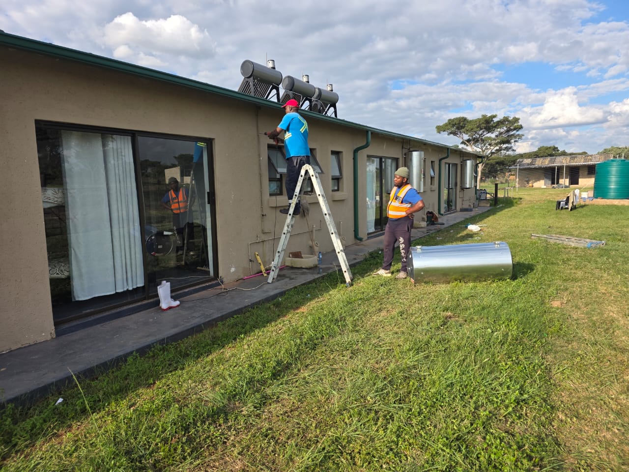 Technicians installing solar water heating units on a building roof